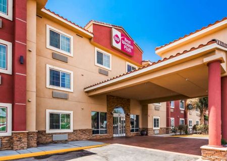 The image shows the entrance of a Best Western Plus hotel with a covered driveway, large windows, and a welcoming entrance.