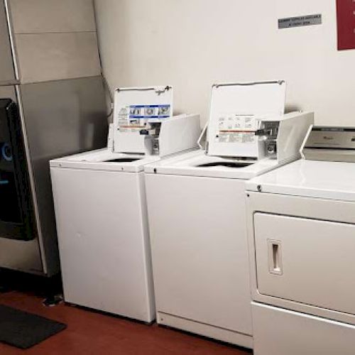 The image shows a small laundry room with washing machines, a dryer, a vending machine, and an ice dispenser.