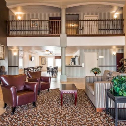 The image shows a hotel lobby with seating areas, a patterned carpet, and a reception desk on the right.