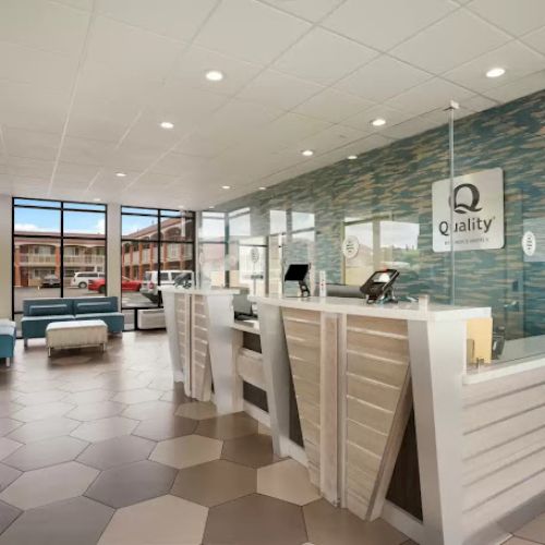 A modern hotel lobby with hexagonal floor tiles, a front desk, and a 