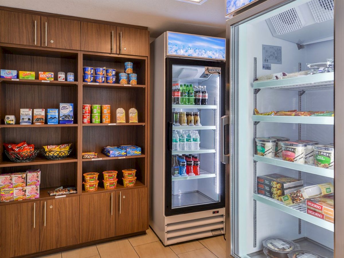 A small convenience store section with shelves of snacks, a refrigerated drinks display, and a cooler containing various food items.