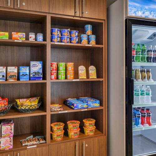 The image shows shelves with snacks and canned goods, and a refrigerator stocked with various bottled drinks.