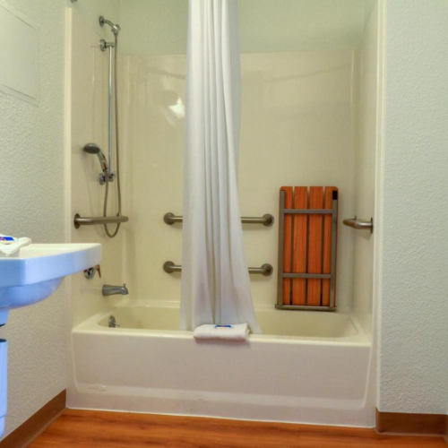 The image shows a bathroom with a bathtub and shower, equipped with grab bars, a shower curtain, sink, and a towel on a rack on the wall.