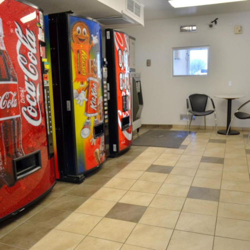 The image shows a break room with vending machines, a small table with two chairs, and a microwave on a counter.