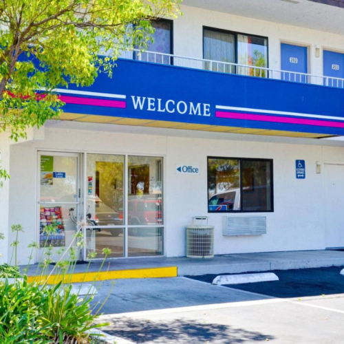 The image shows the entrance to a motel with a sign saying 