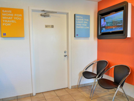 A lobby area with a door, two chairs, a wall-mounted TV, and motivational posters.